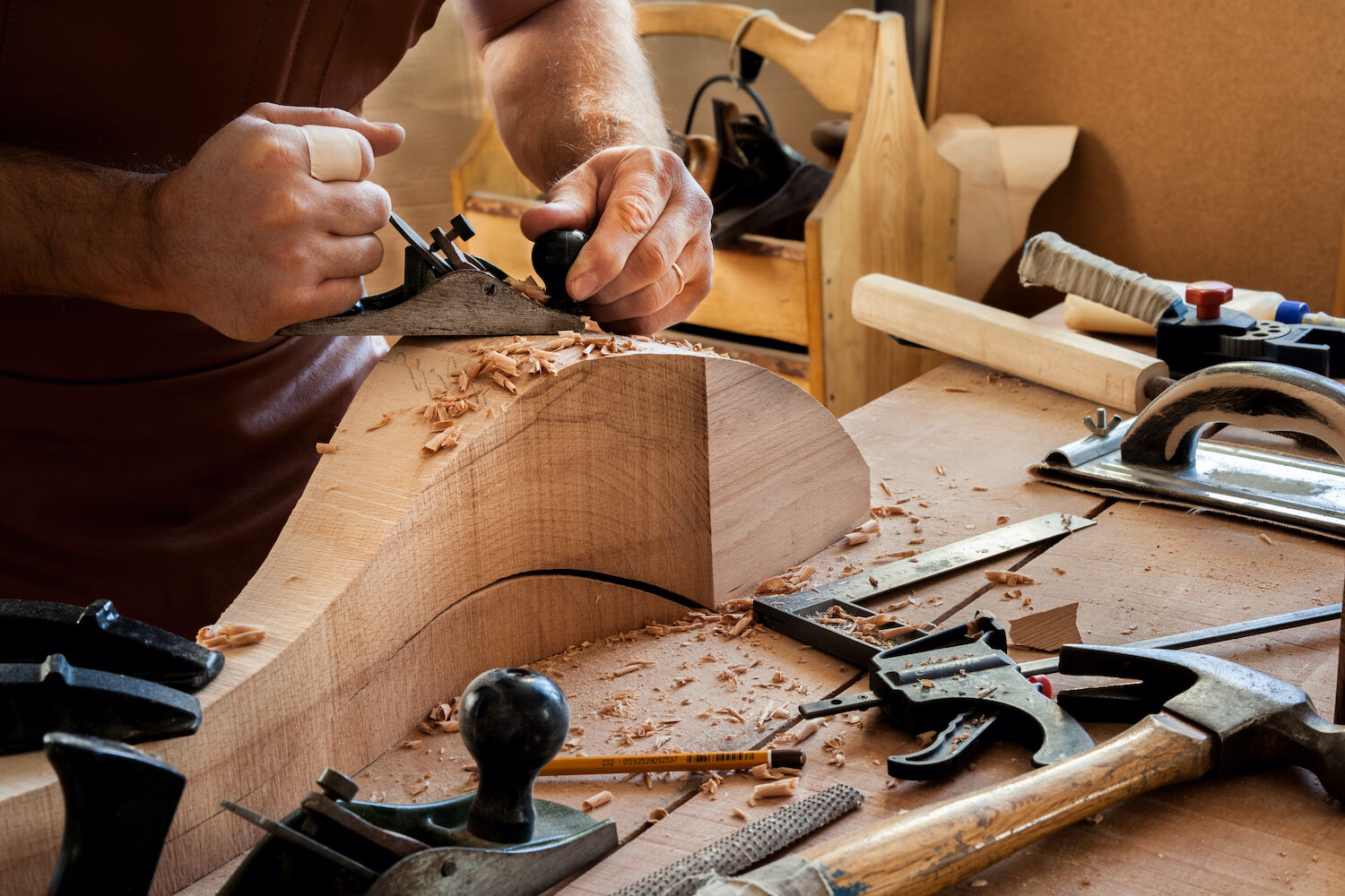 Manos de carpintero cepillando una pieza curva de madera